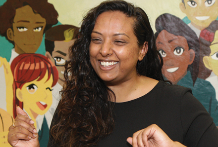 teacher smiling in front of a mural